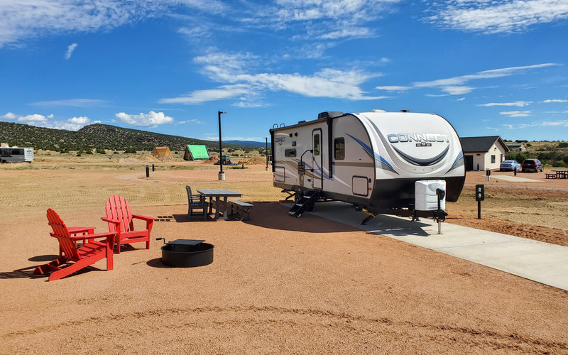Camper on a back-in RV site at Observer Ranch with red Adirondack chairs and mountain views