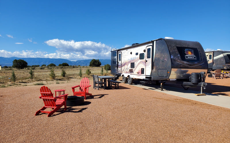 Jupiter planet camper with red Adirondack chairs and fire ring at Observer Ranch