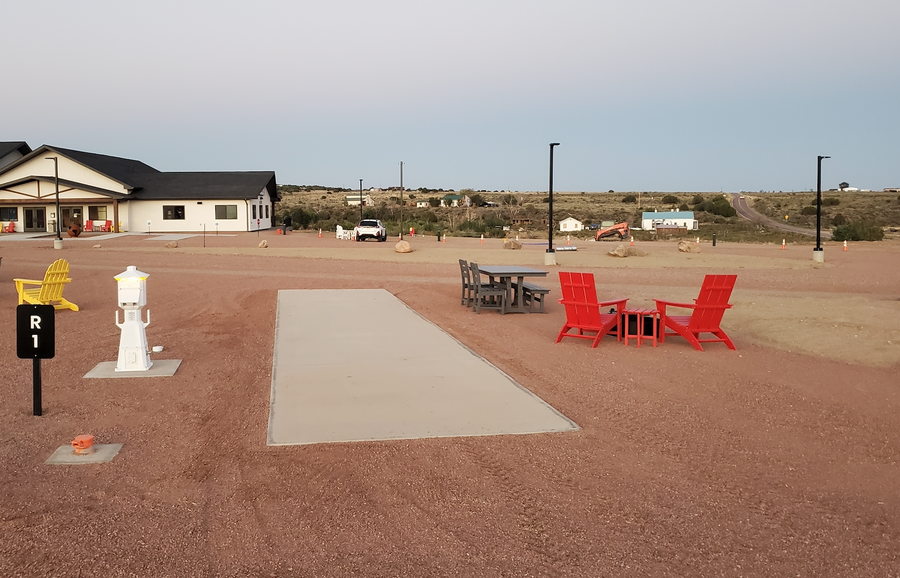 Premium pull-through Harvest Host RV site R1 with concrete pad and Adirondack chairs