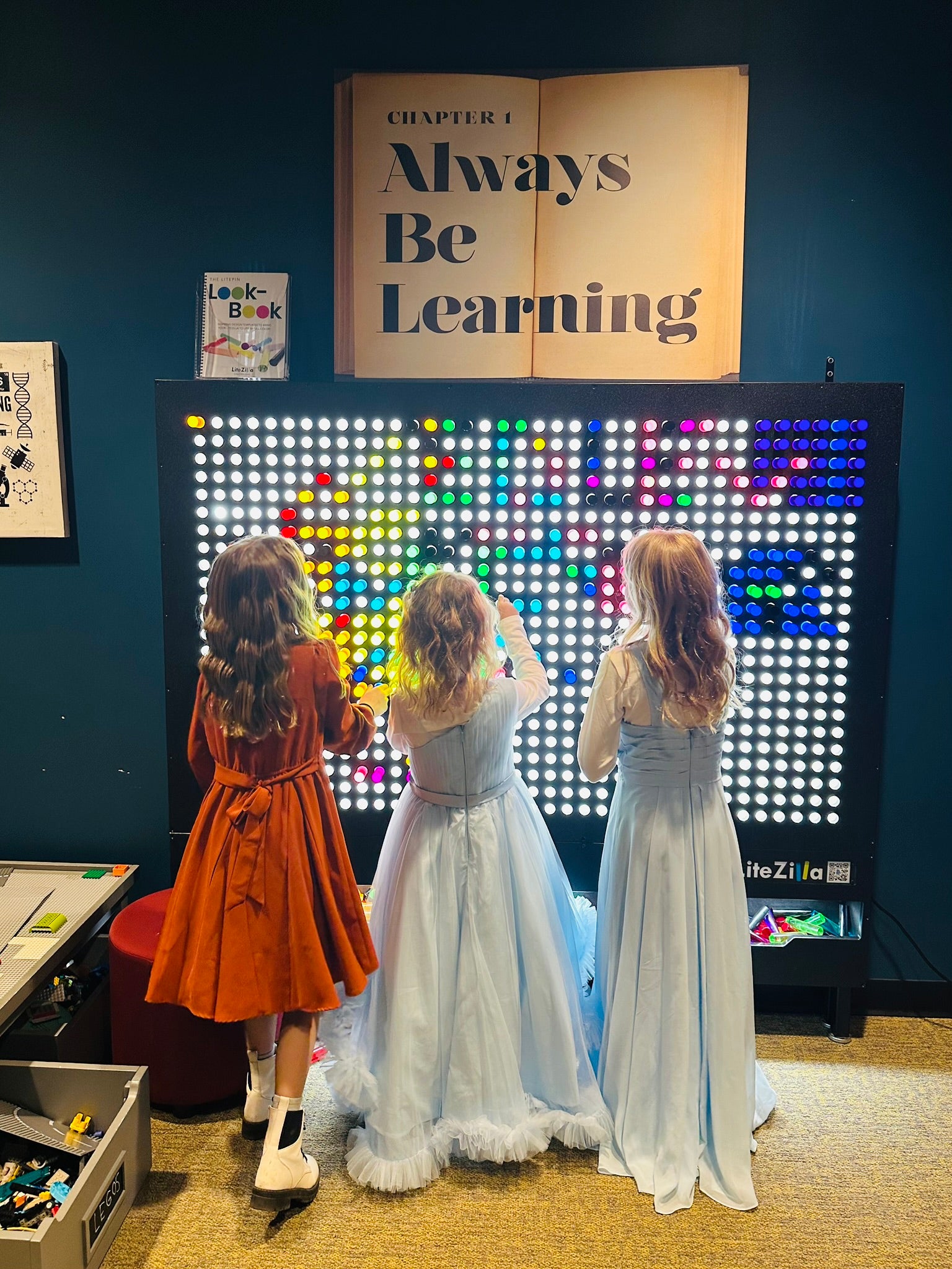 Kids at the Always Be Learning light wall inside the Little Spark Learning Center