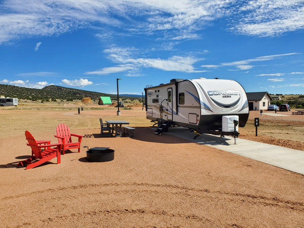 Coachmen camper on a Select back-in RV site at Observer Ranch with red Adirondack chairs and mountain views