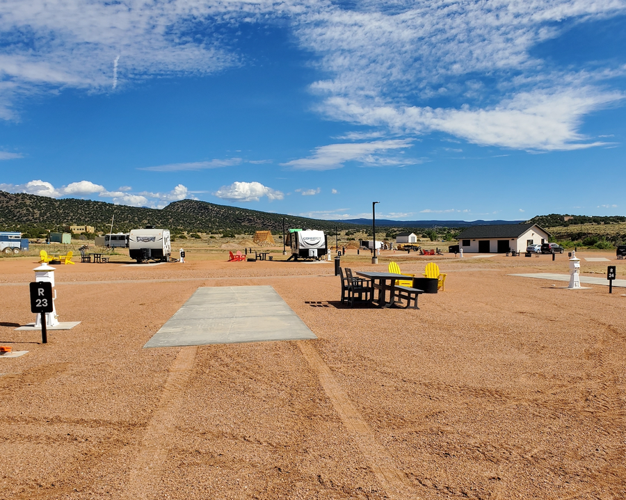 Signature pull-through RV site 23 with yellow Adirondack chairs near the bathhouse at Observer Ranch